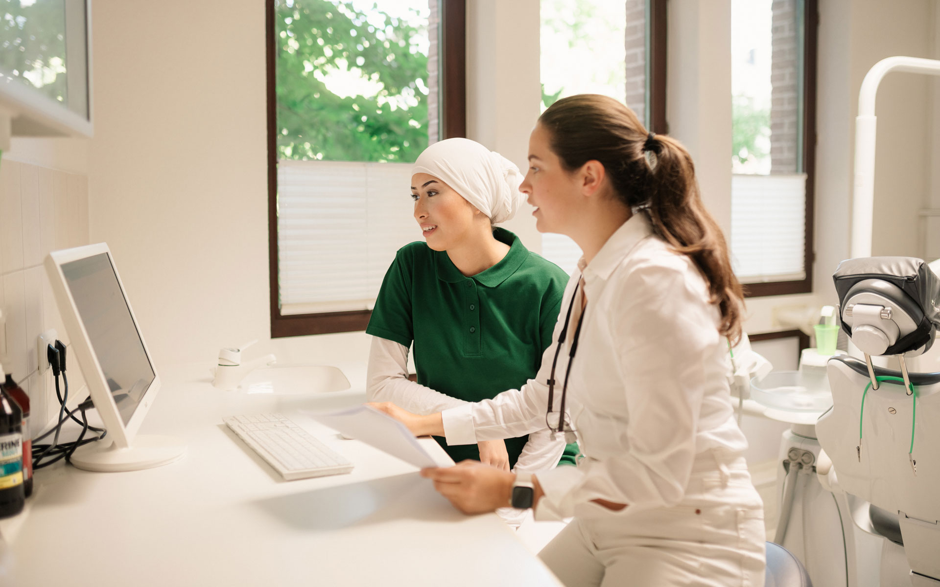 Zahnärztin und ZFA besprechen Patienteninfo in Zahnarztpraxis Aachen